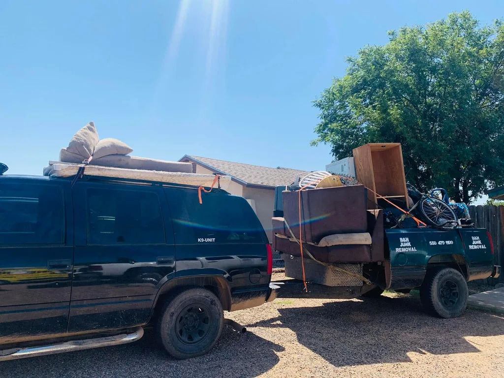 The B&H Junk Removal truck and trailer loaded with a sofa, cabinets and a bicycle